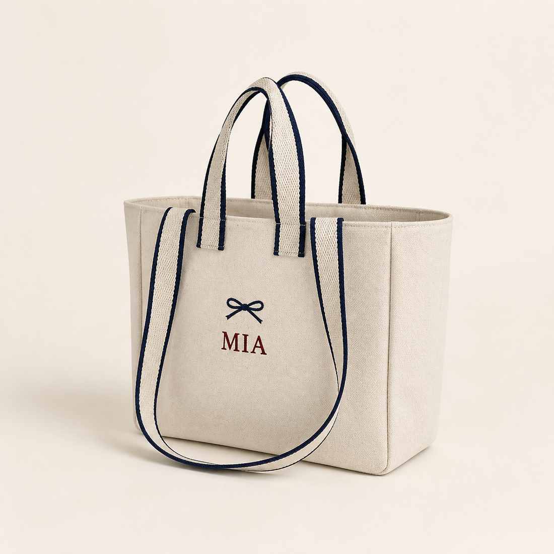 Off White contrast-strap canvas tote with example navy bow and MIA embroidery, angled view
