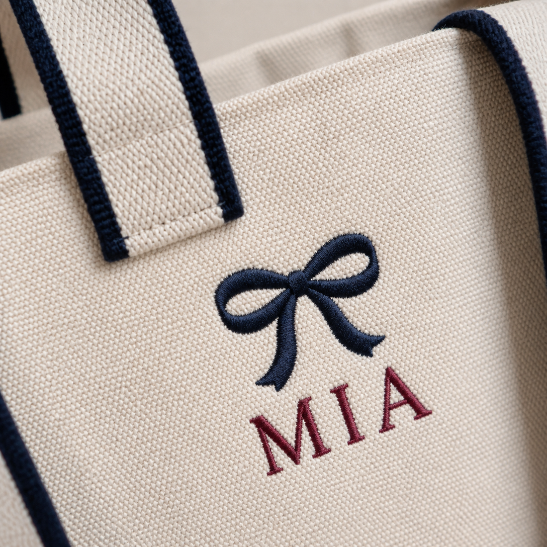 Close-up of example navy bow and burgundy MIA embroidery on the Off White contrast-strap canvas tote
